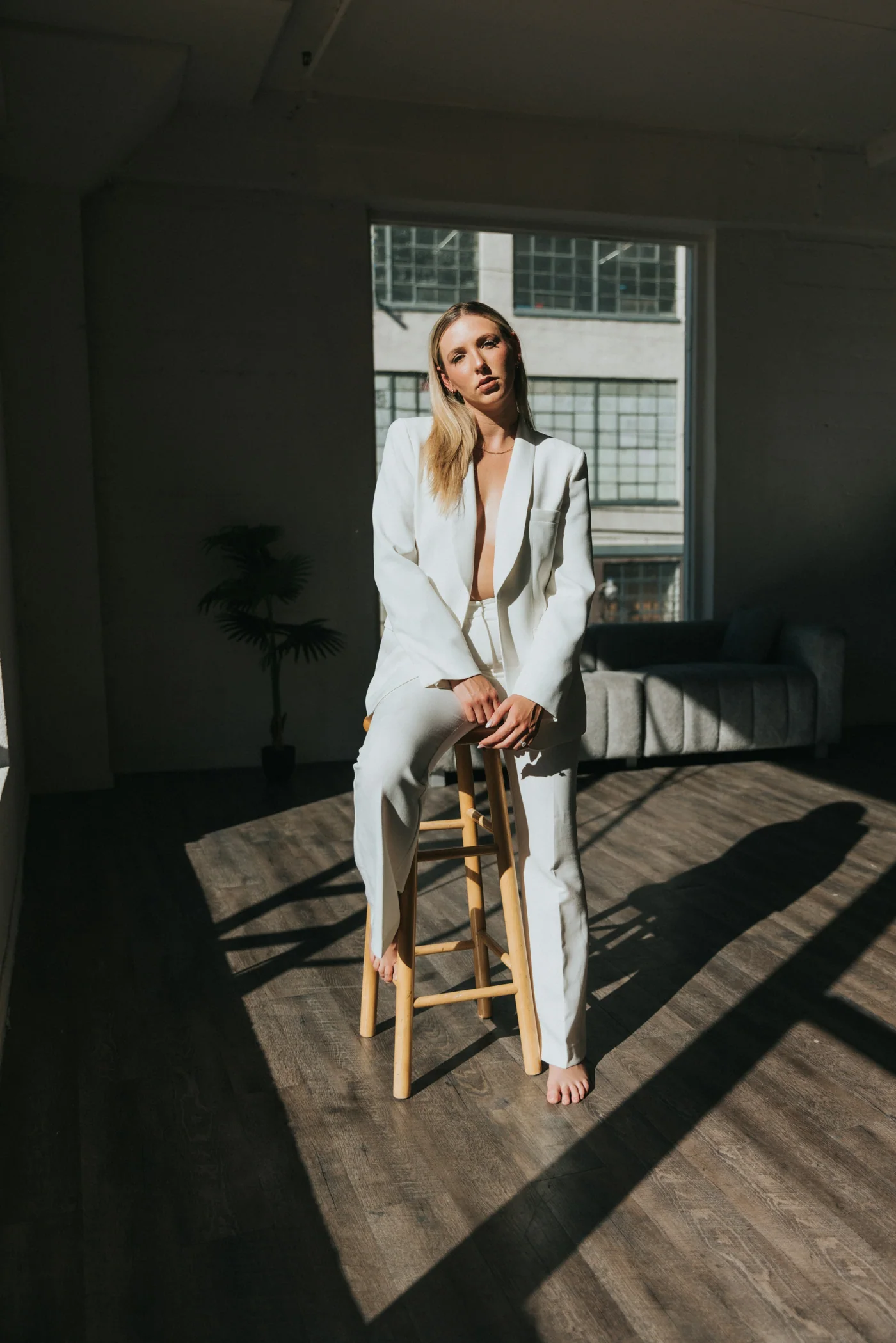 A woman in a white suit seated on a stool