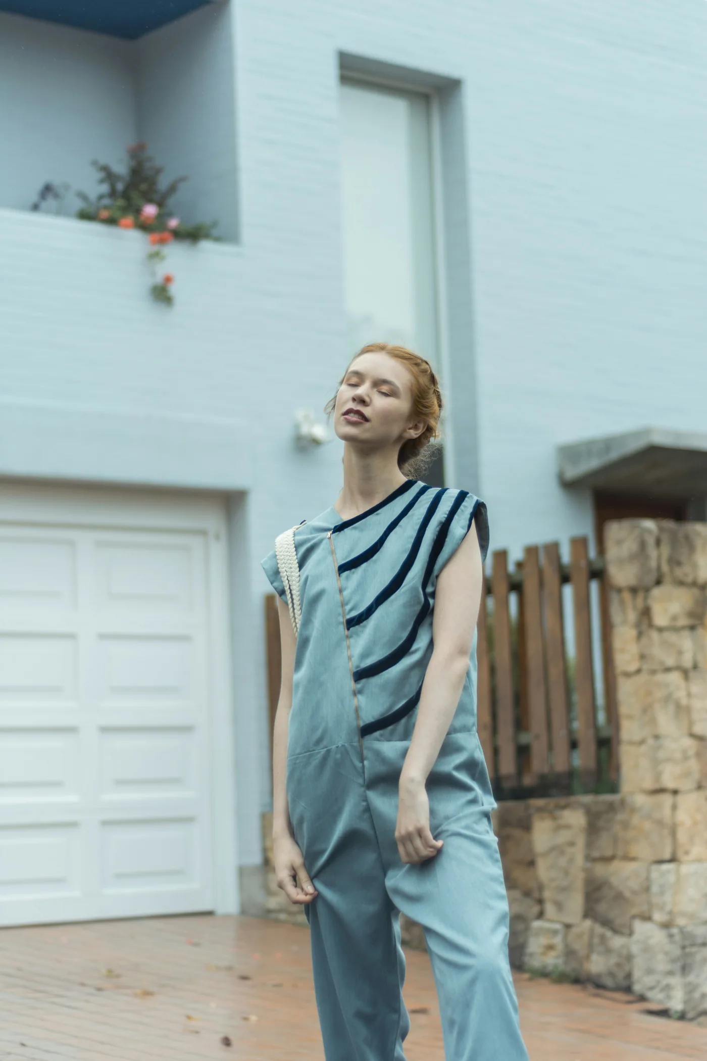 A woman standing near a pale house
